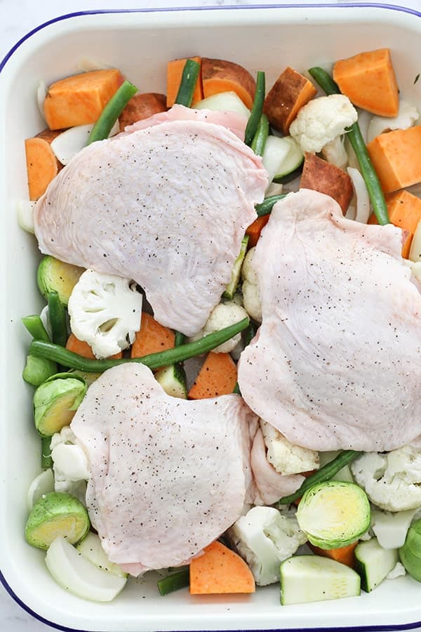 chicken thighs laying on a bed of vegetables skin-side up