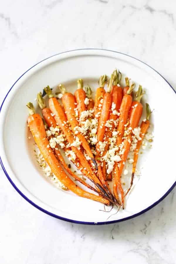 roasted carrots on a white plate with feta and dukkah sprinkled on top 