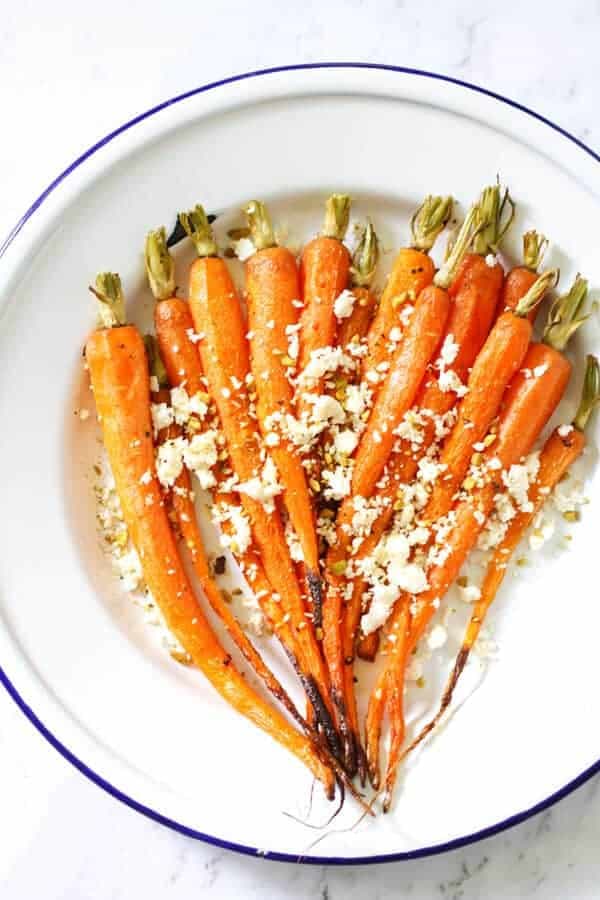 roasted carrots on a white plate with feta and dukkah sprinkled on top 