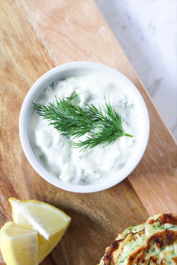 Greek Tzatziki in a white bowl with a sprig of dill on top