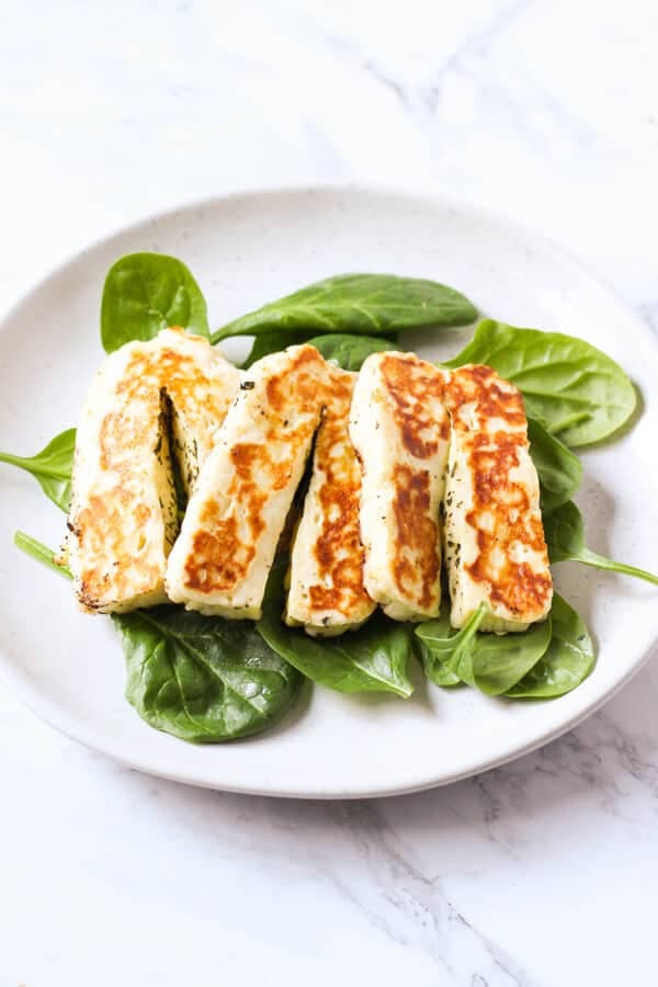 grilled halloumi on a bed of spinach leaves.