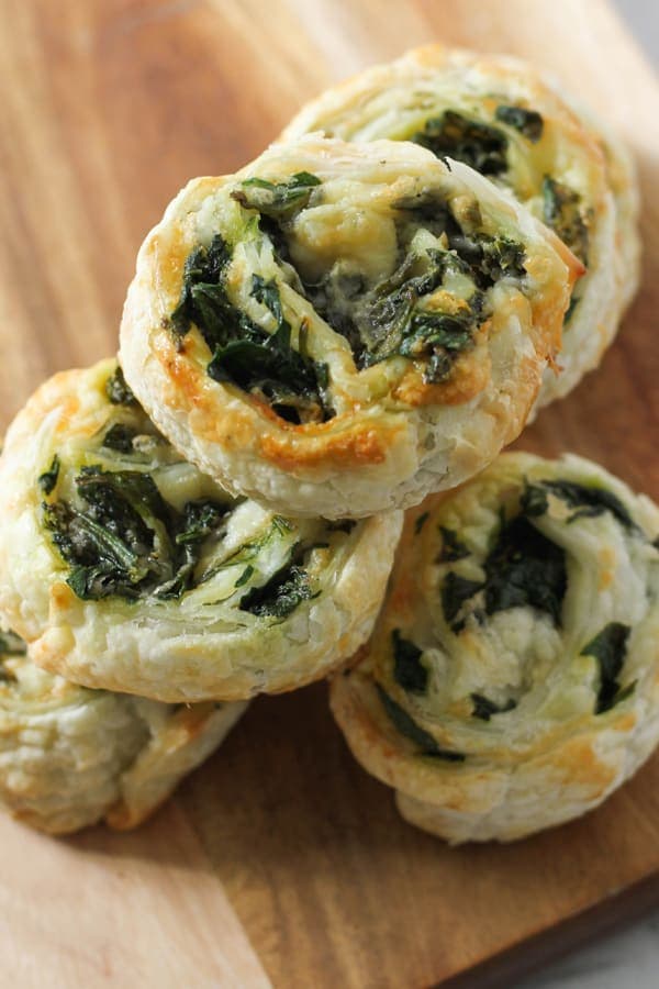 spinach and feta pinwheels on a wooden serving board.