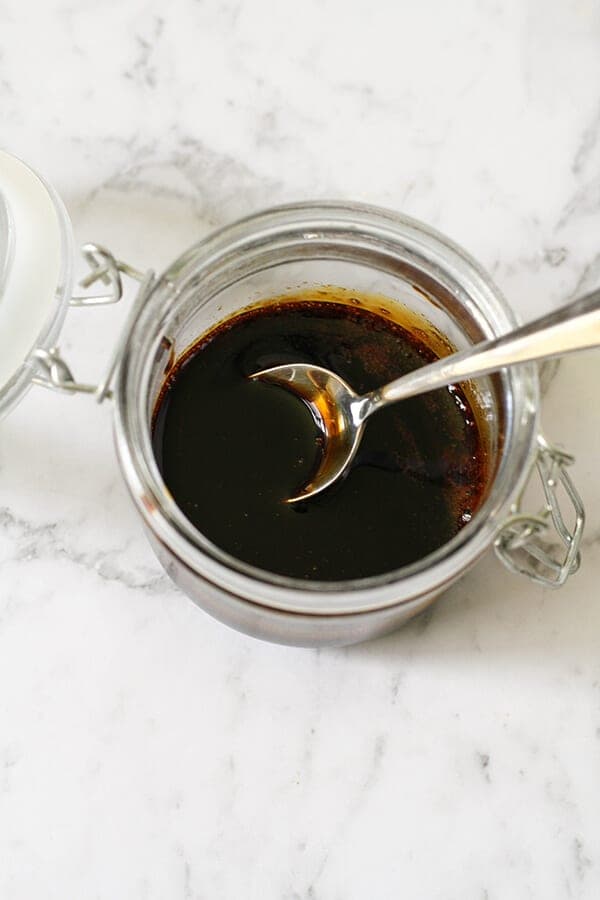 balsamic glaze in an open glass jar with a spoon inside it.