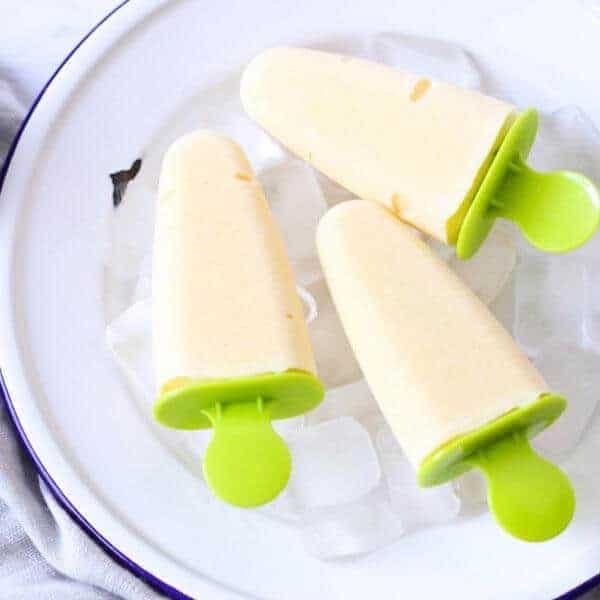 3 mango popsicles on a bed of ice cubes.