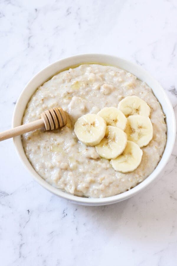 a bowl of oatmeal topped with banana slices and honey.
