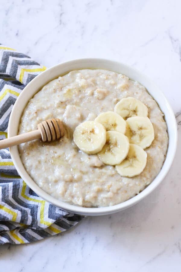 a bowl of oatmeal topped with banana slices and honey.