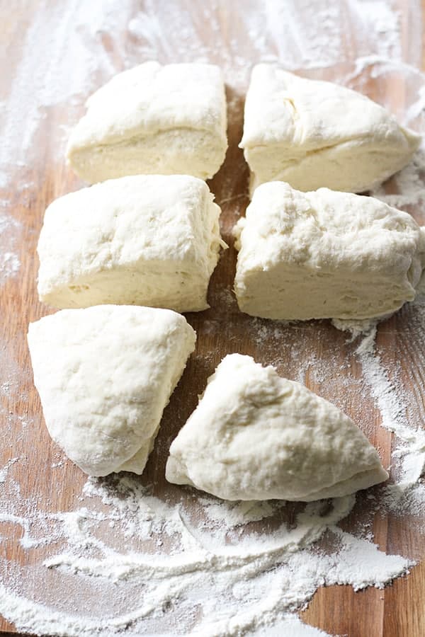 dough cut into 6 pieces on a wooden cutting board.