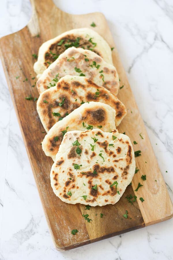 yoghurt flatbreads stacked on top of each other on a wooden board.