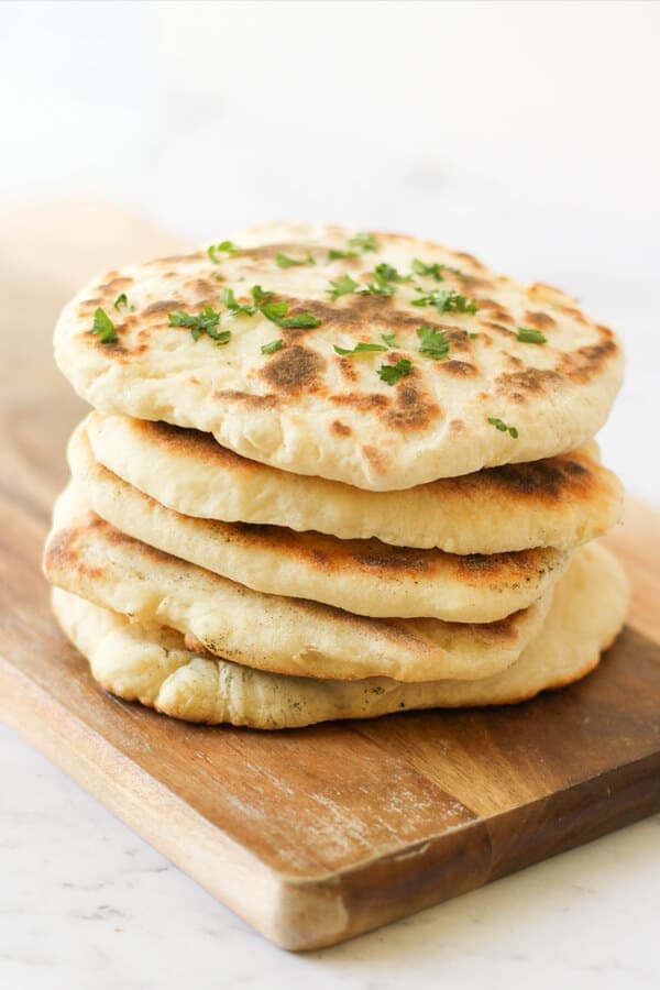 yoghurt flatbreads stacked on top of each other on a wooden board.