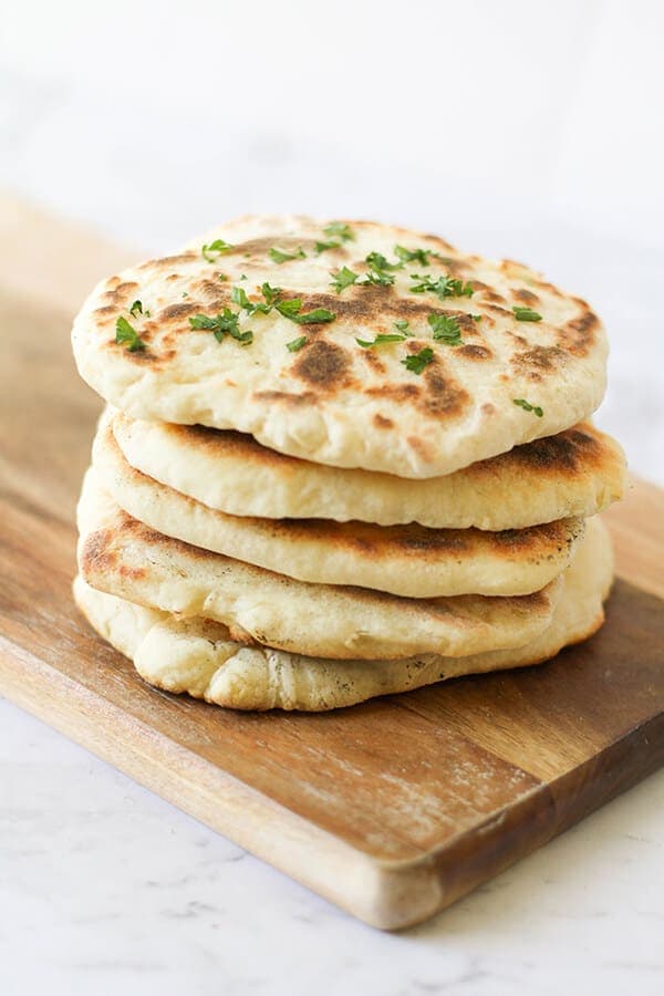 yoghurt flatbreads stacked on top of each other on a wooden board.