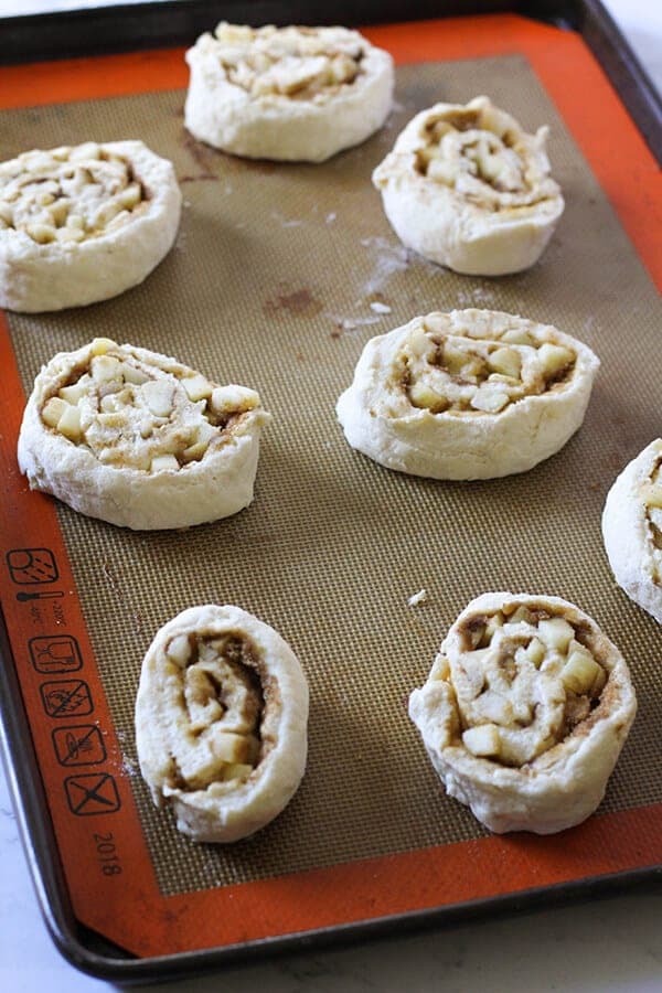 apple cinnamon rolls on a baking tray ready for the oven. 