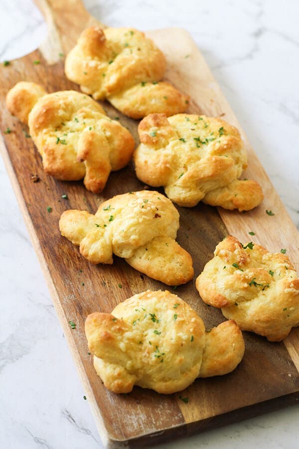 garlic knots on a wooden serving board.