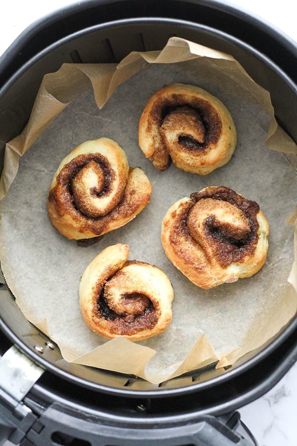 cinnamon rolls in an air fryer basket.