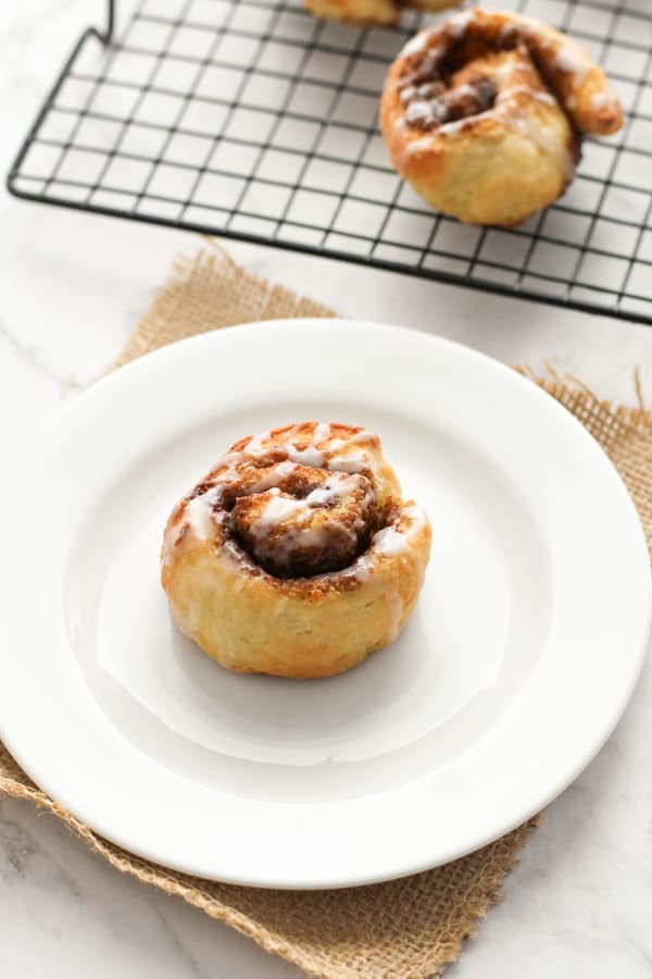cinnamon rolls on a white plate covered in glaze.