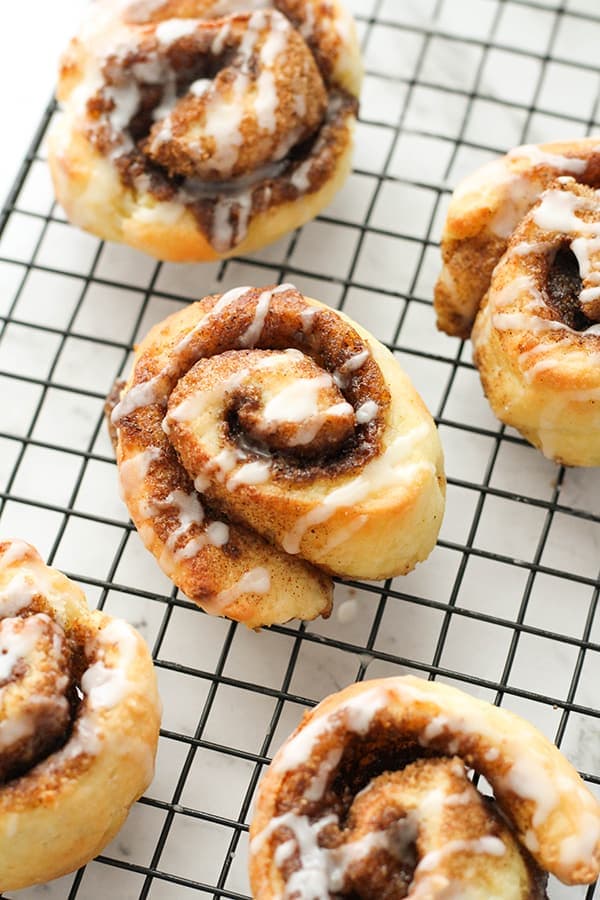 cinnamon rolls on a wire rack covered with glaze.