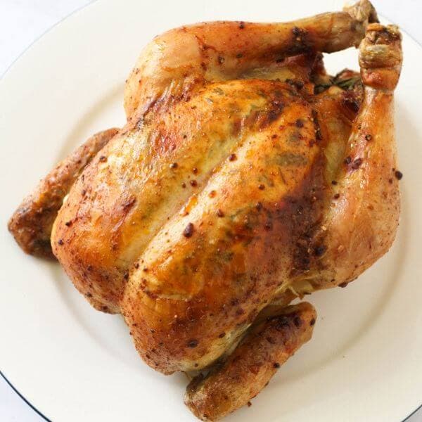 Whole roast chicken on a white plate.