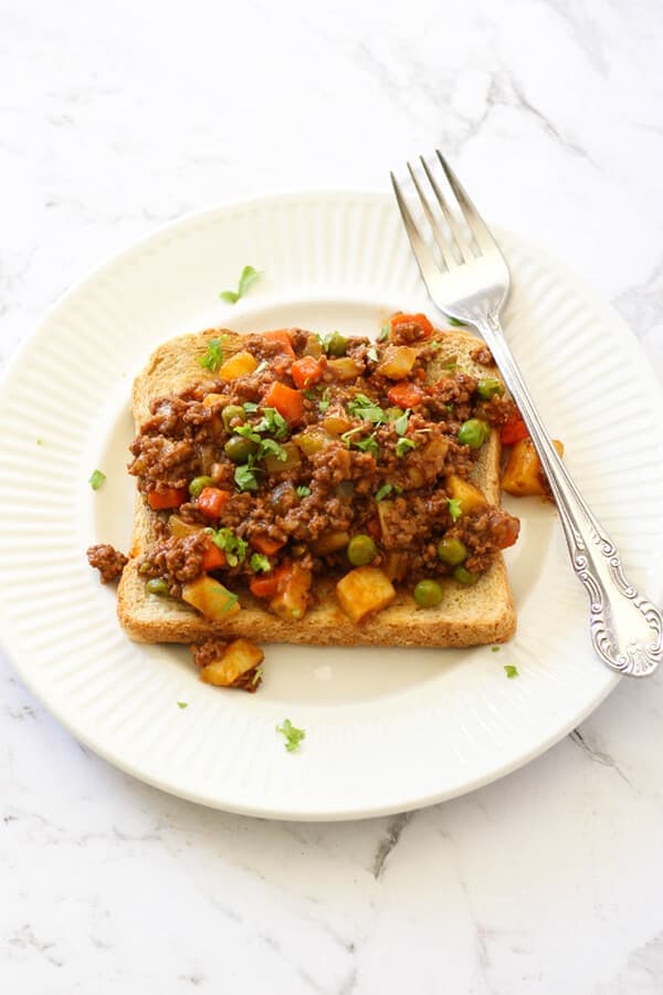 Savoury mince on top of a piece of toast on a white plate.