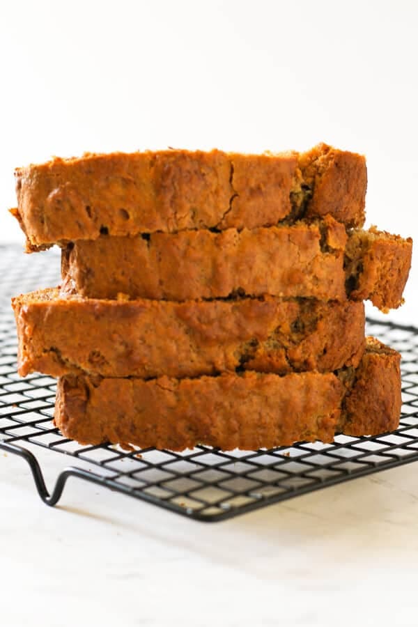 Banana bread slices stacked on a wire cooling rack.