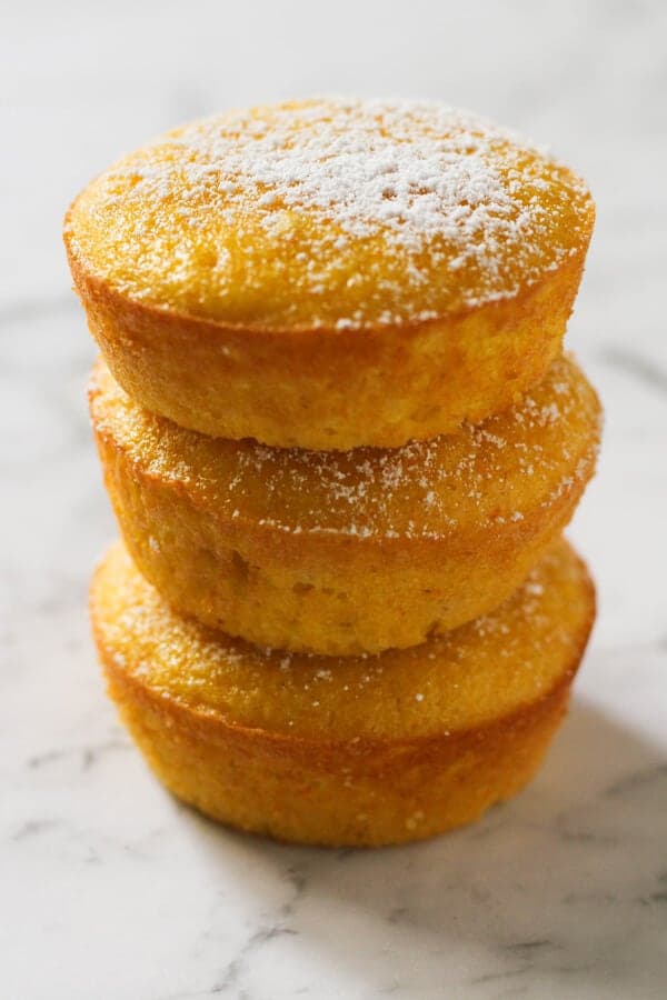 Orange and almond cakes stacked on top of each other on a marble board.