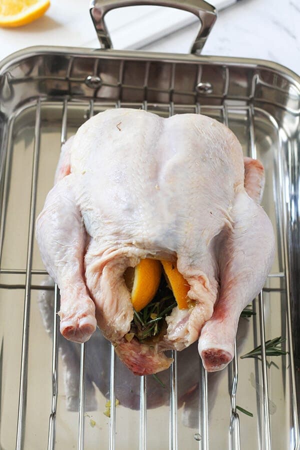 whole chicken stuffed with lemon wedges and rosemary ready for the oven.