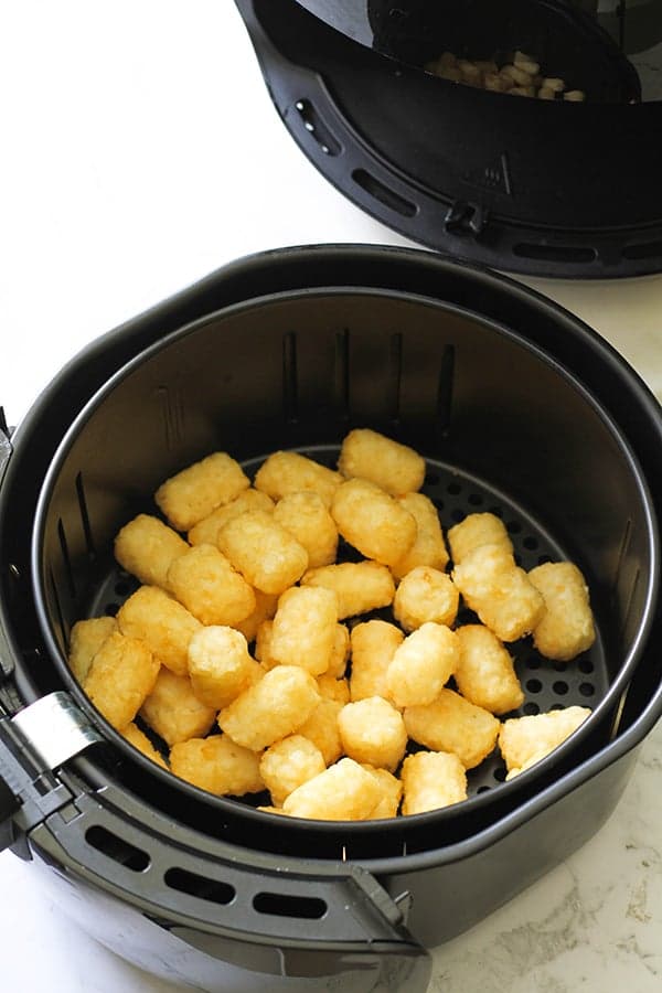 Air fryer basket filled with tater tots.