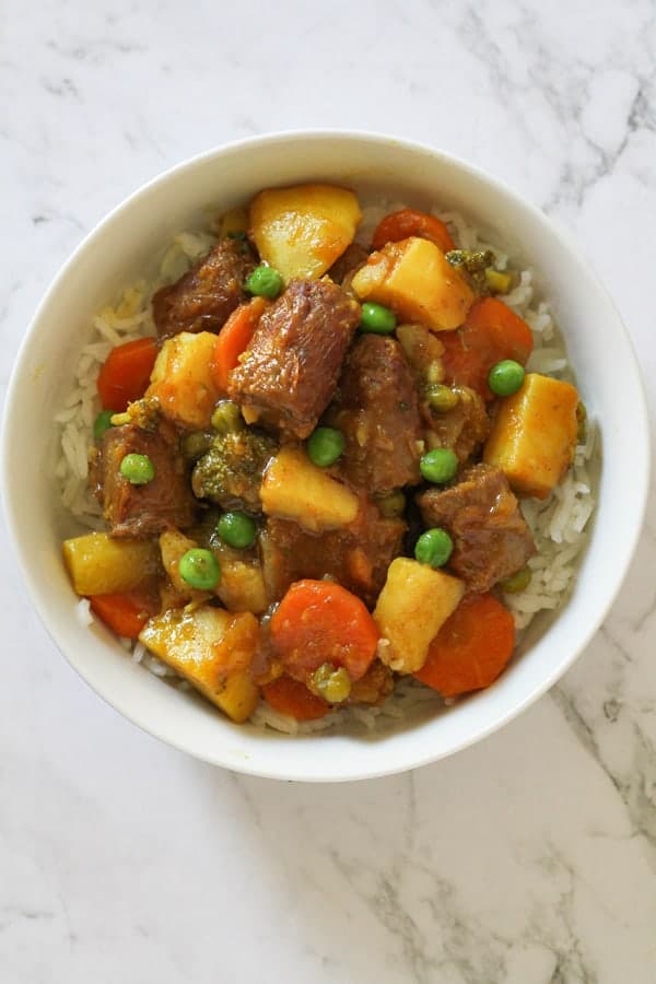 curried sausages on a bed of rice in a white bowl. 