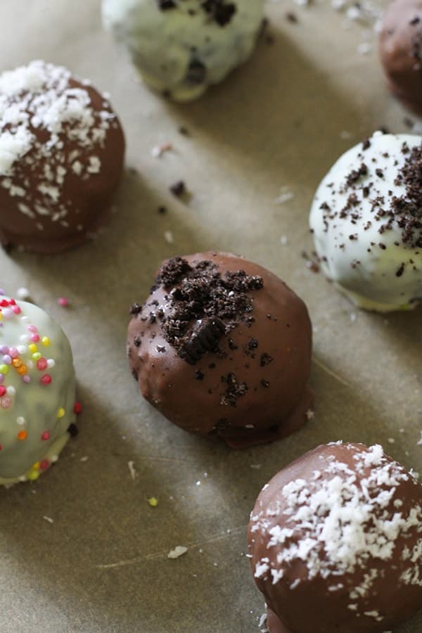 oreo balls laying on baking tray covered in cookie crumbs and sprinkles.