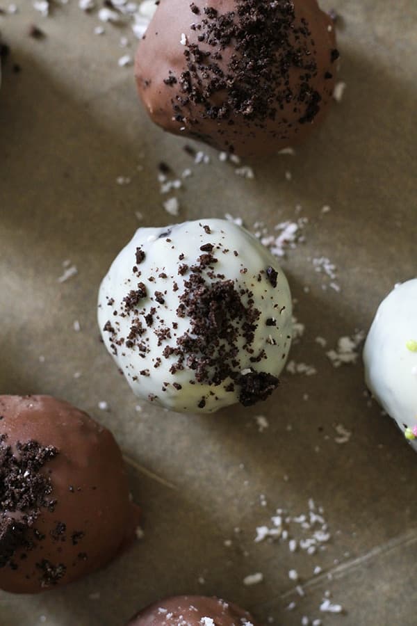 oreo balls laying on baking tray covered in cookie crumbs and sprinkles.