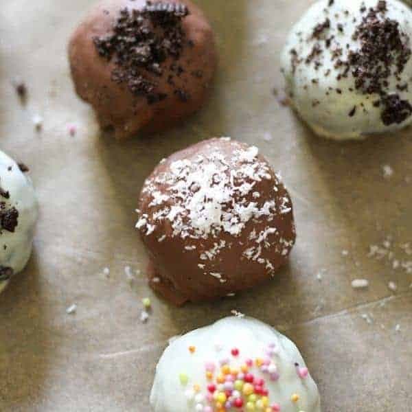 oreo balls laying on baking tray covered in cookie crumbs and sprinkles.