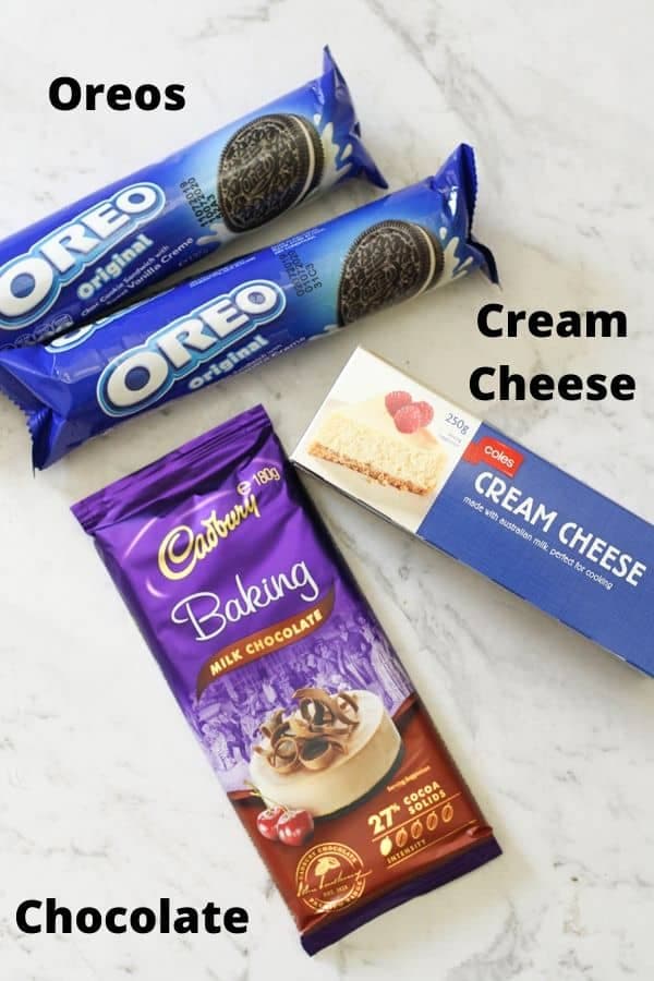 ingredients for oreo balls laid on a white marble background.