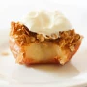 baked apple topped with ice cream on a white plate.