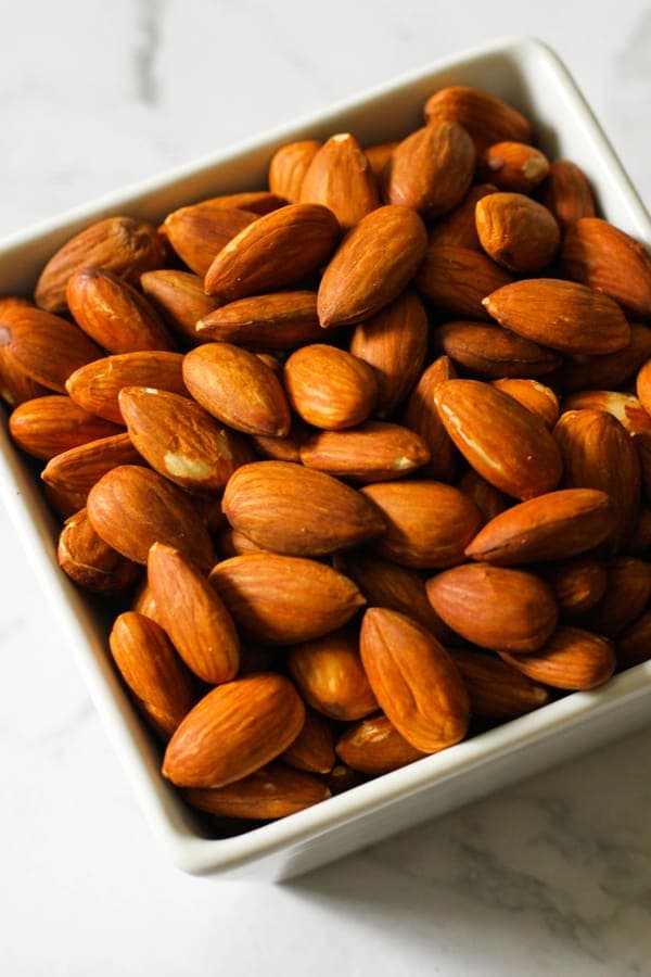 Roasted almonds in a white square serving bowl.