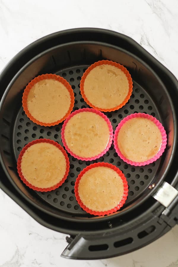batter in silicone muffin cases inside an air fryer basket.