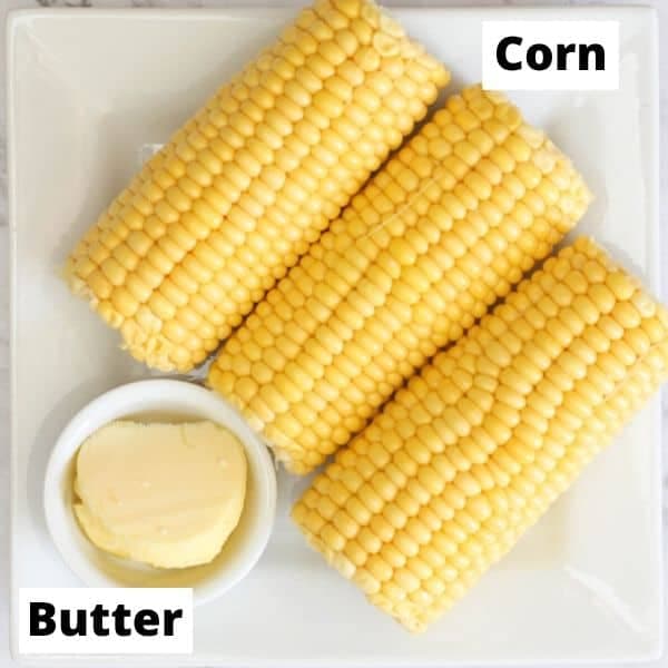 3 ears of corn and some butter on a white plate.