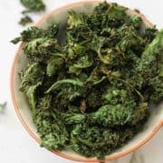 sweet and salty kale chips in a white bowl.