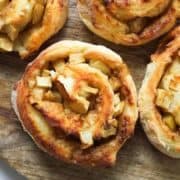air fryer apple cinnamon rolls on a wooden cutting board.