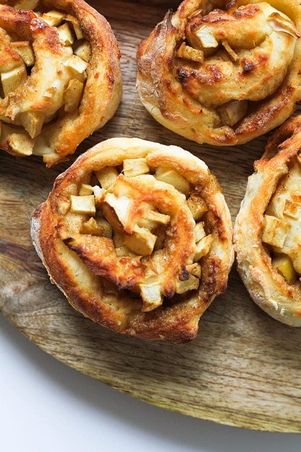 air fryer apple cinnamon rolls on a wooden cutting board.