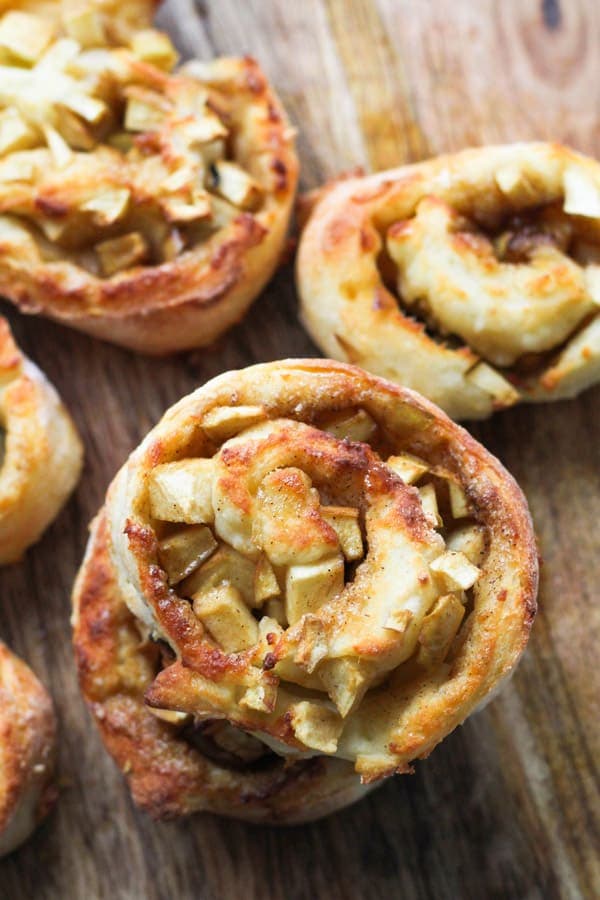 air fryer apple cinnamon rolls on a wooden cutting board.