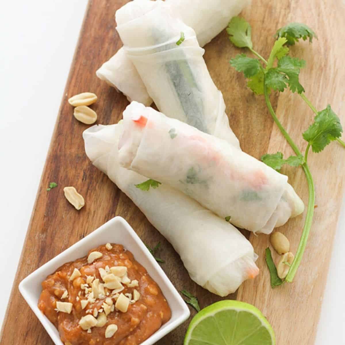 chicken rice paper rolls on a wooden serving board.
