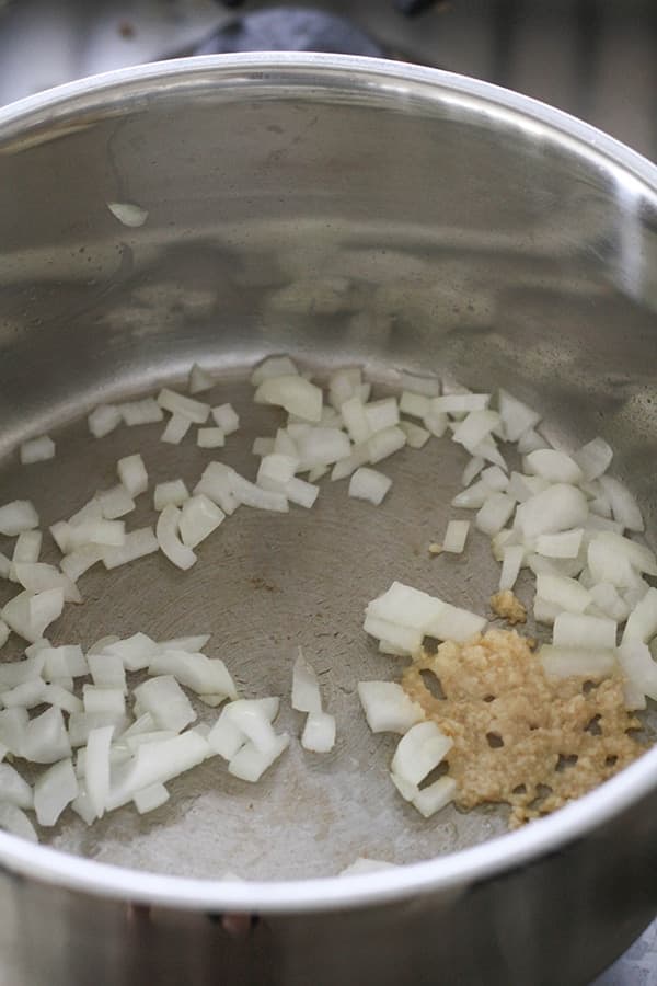 diced onion and garlic being sautéd in a pot.
