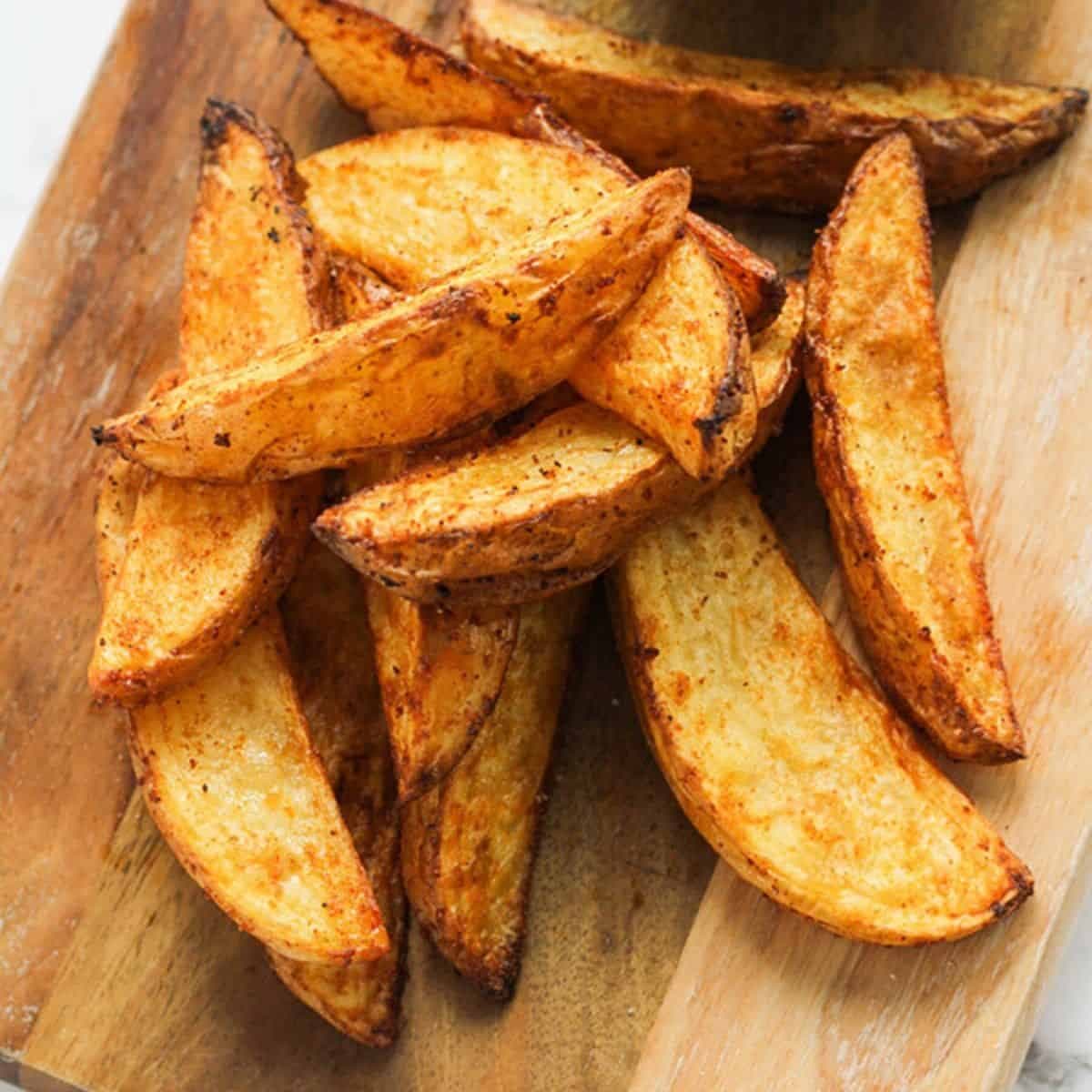 potato wedges on a wooden cutting board.