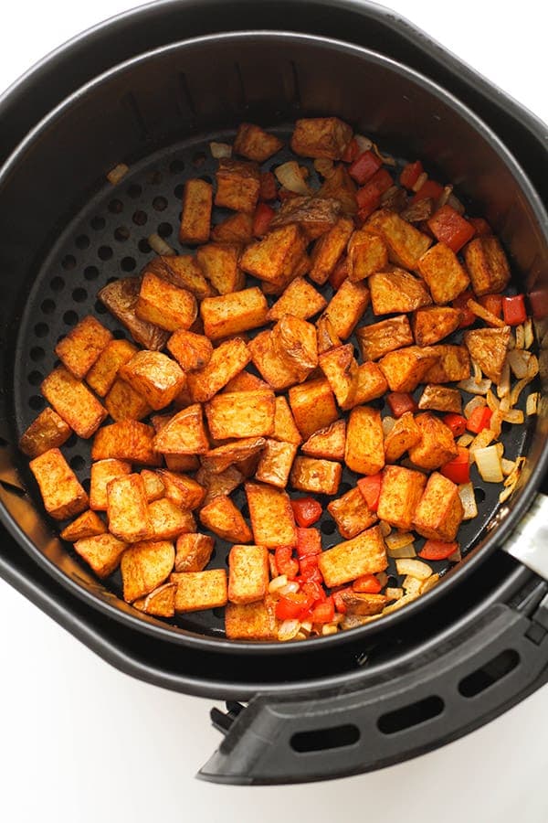 breakfast potatoes in an air fryer basket.