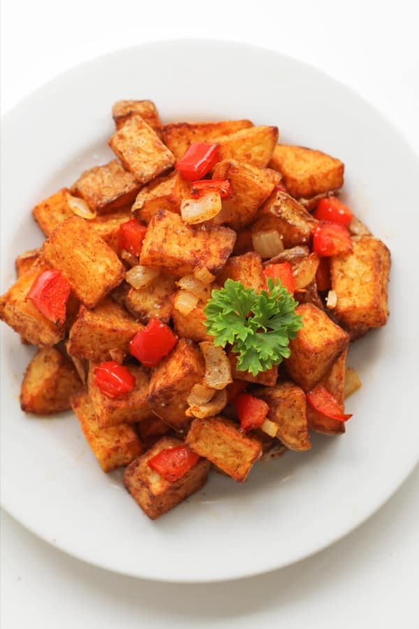 breakfast potatoes on a white plate topped with parsley.