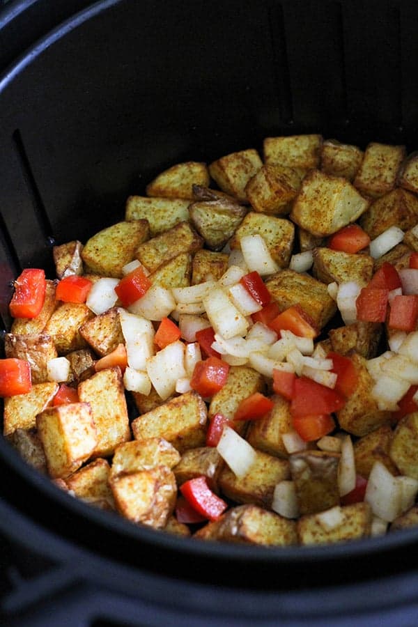 potatoes, capsicum and onion in an air fryer basket.