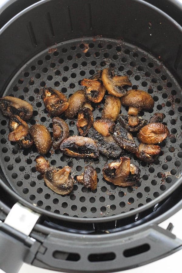 cooked mushrooms in an air fryer basket.