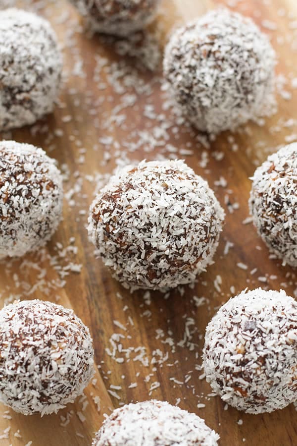 chocolate coconut energy balls on a wooden serving board.