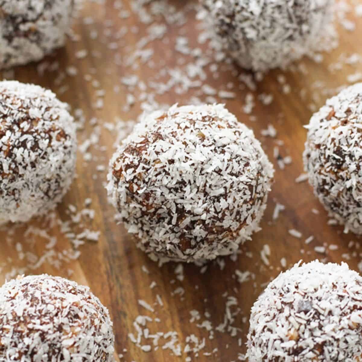 chocolate coconut energy balls on a wooden serving board.