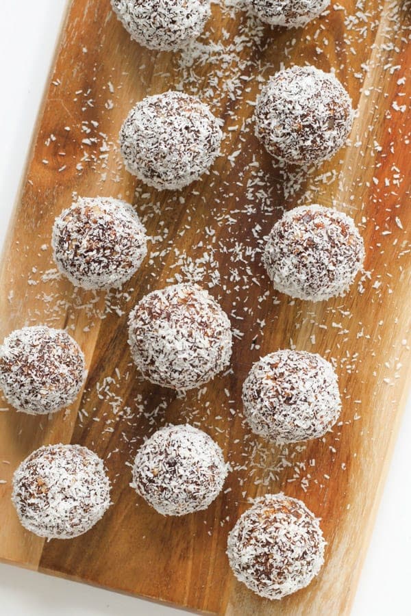 chocolate coconut energy balls on a wooden serving board.