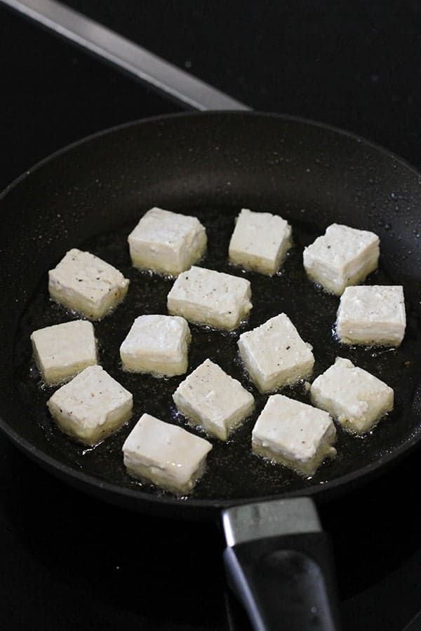 cubes of tofu being fried in a frying pan.