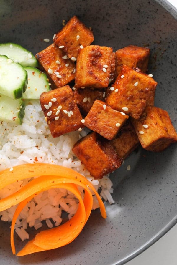 cubes of sriracha tofu on top of a bed of rice.